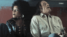 a man and a woman are sitting next to each other and the man is holding a gun and the woman is looking up