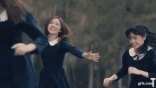 a group of young women in school uniforms are dancing together in a park .