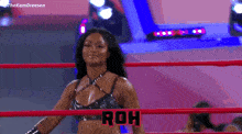 a woman is flexing her muscles in a wrestling ring while wearing a black top .