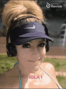 a woman wearing headphones and a nike visor says hola in pink letters