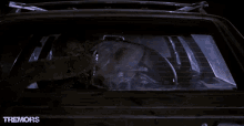 a movie poster for tremors shows a monster in a car