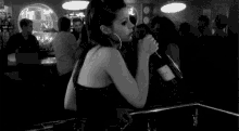 a woman is drinking from a large bottle of wine in a bar .