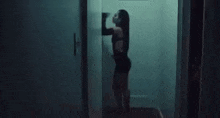 a woman in a black dress is leaning against a wall in a dark room .