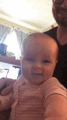 a man is holding a baby in his arms and the baby is smiling at the camera