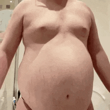 a man with a very large belly is standing in a bathroom .