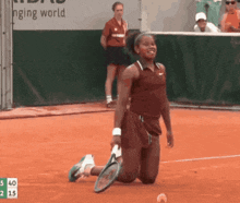 a tennis player is kneeling down on the court with a scoreboard behind her that says changing world