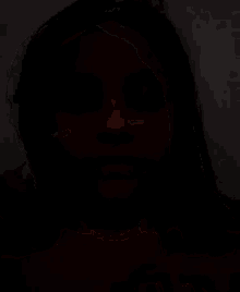 a young girl is wearing a red shirt and making a sad face .