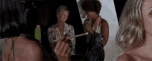 a group of women are standing next to each other in a dark room . one of the women is holding a piece of paper .