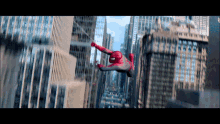 a man in a spiderman costume is flying through the air over a city