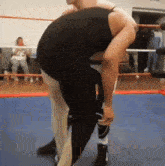 a man in a black tank top is lifting another man in a wrestling ring ..