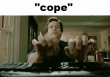a man is sitting in front of a remote control with his hands outstretched and the words " cope " above him .