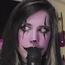 a woman with makeup on her face is holding a microphone in her mouth .