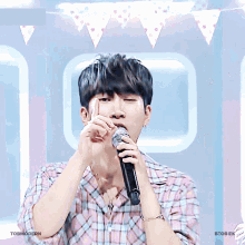 a young man singing into a microphone with the words tobmodern written below him