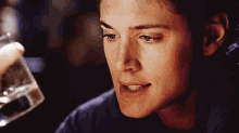 a close up of a man 's face holding a glass