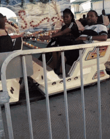 a man and woman are riding a roller coaster at a carnival