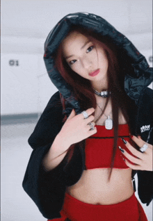 a woman wearing a red top and a black jacket with the word adidas on it