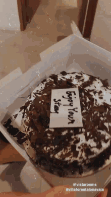 a cake in a box with a card that says " enjoy your stay "