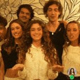 a group of young people are posing for a picture in front of a wall with flowers on it .