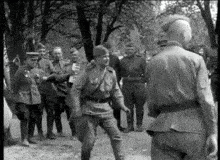 a black and white photo of a group of soldiers standing next to each other on a street .