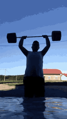 a man is lifting a barbell over his head in front of a building
