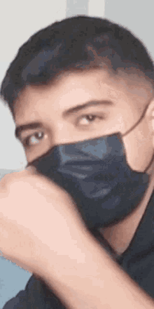 a close up of a man wearing a black face mask covering his mouth .