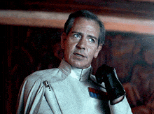 a man wearing a white uniform and a black glove has a patch on his chest that says ' emperor ' on it