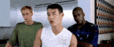 a man wearing a balls models shirt talks to two other men