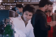a man in a white shirt is sitting at a bar talking to a group of people .