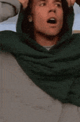 a close up of a man wearing a green hoodie .