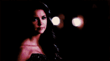 a woman in a black dress is looking at the camera