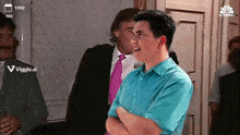 a man in a blue shirt with his arms crossed stands in front of a cnbc advertisement