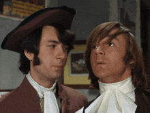 a man in a pirate hat looks at another man