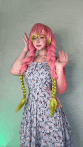 a woman with pink hair and green braids is wearing a floral dress .