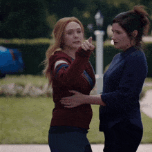 two women are standing next to each other one is pointing