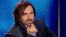 a man with a beard holds a pen in his hand and says " puuutain 1 "
