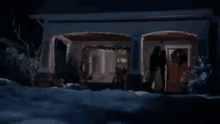 a couple kissing in front of a house with christmas lights on it