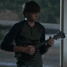 a young man is holding a mandolin in his right hand