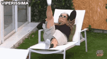 a man is laying on a lawn chair with his legs up .
