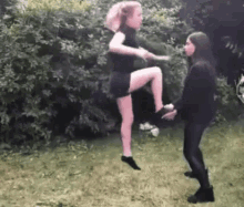 two women are standing next to each other on the grass .