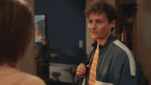 a man in a denim jacket and tie looks at a woman