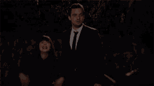 a man in a suit and tie stands next to a woman who is singing