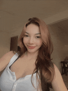 a woman in a white tank top takes a selfie in a room