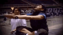 a man is sitting on the floor with his arms outstretched while a woman looks on