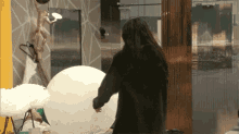 a woman in a black coat is holding a large white balloon