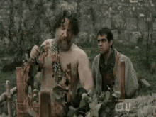 a man without a shirt is standing in a field with a sign that says cw on it