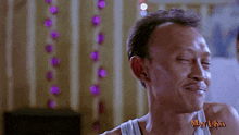 a man in a white tank top with the word man laksa on his chest