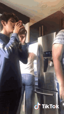 a group of people standing in front of a refrigerator with a tiktok logo on the bottom right