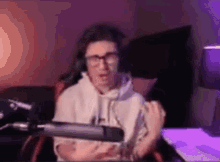 a man wearing glasses is sitting in front of a microphone in a room .