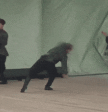 a group of men in military uniforms are dancing on a stage in front of a green curtain .