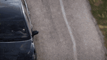 a black car is driving down a road with a white line on it